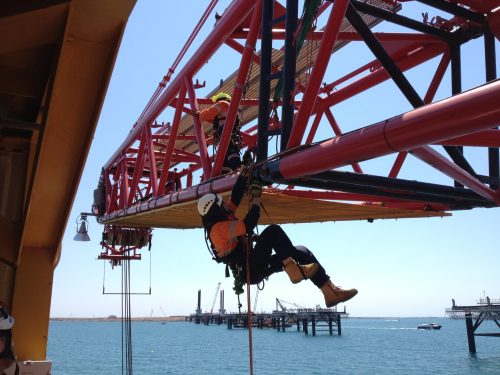 A vertech IRATA rope access technician is carrying out testing on marine lifting equipment located on an offshore barge.