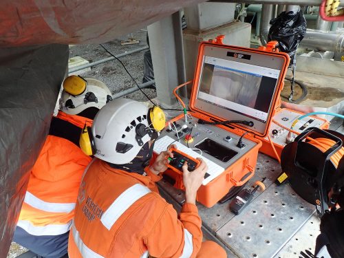 Two vertech RDVI technicians controlling a crawler robotic via an electronic case with a screen.