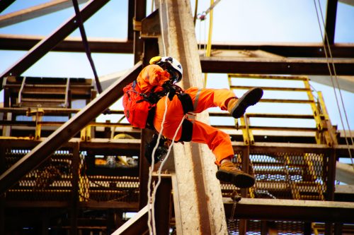 An IRATA rope access technician descending from an offshore derrick structure during a decommissioning project.