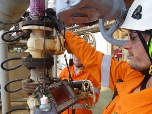 Two Vertech technicians are carrying out eddy current testing on some piping.