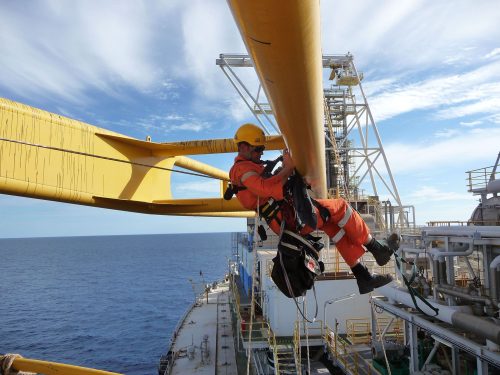 A vertech IRATA rope access technician hangs suspended from some structural beams onboard the fpso.