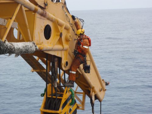 A Vertech IRATA rope access technician is working on the head of a crane.