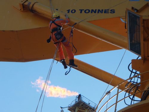A Vertech IRATA rope access technician is working on the head of a crane.