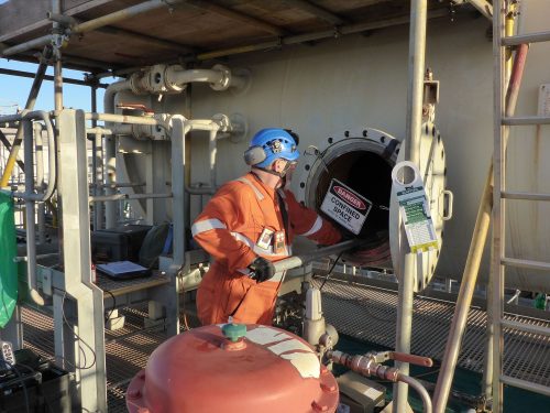 A Vertech technician inserting a camera on a pole into the open access tunnel of a pressure tank as part of a testing regime.