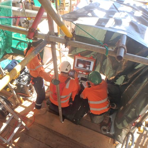 Three vertech technicians gather around a screen to track the progress of the RDVI crawler as part of a testing regime.