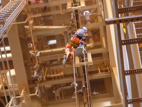 A Vertech IRATA rope access tradesman abseiling from a LNG facility pipe rackloading=