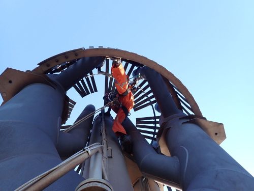 Below view of a vertech IRATA rope access technician carrying out non-destructive testing on a flare tip.