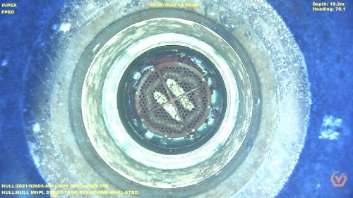 Underwater inspection image of the "INPEX FPSO" vessel's component at a depth of 19.2 meters. A circular metal structure with a gridded centre and several marine organisms attached is centred in the frame. The metallic surfaces are partially covered in biofouling. The surrounding water is a deep, dark blue, enhancing the visibility of the structure. On-screen text includes the vessel's name, date, time, depth, heading, and the geo oceans logo.