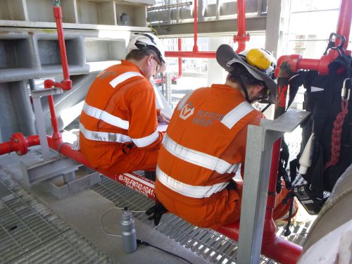 The back view of two vertech technicians sitting and carrying out testing.