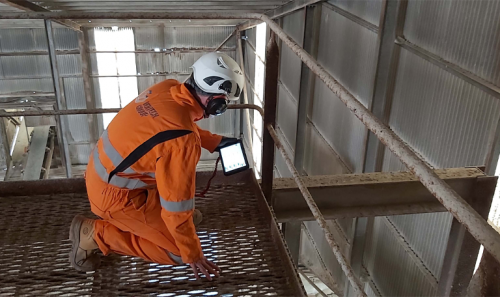 A vertech inspector conducting handrail testing and inspection with a tablet based e-reporting system