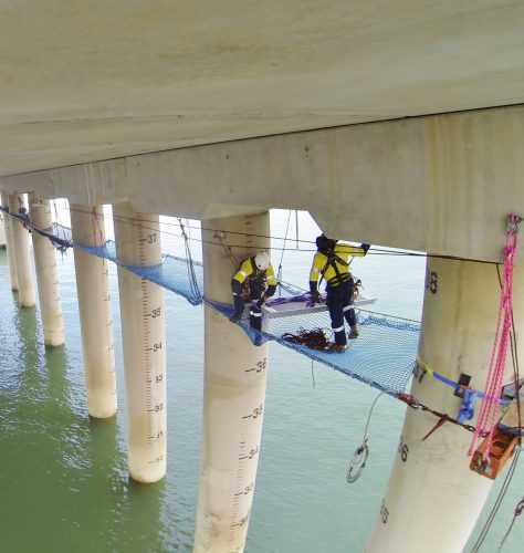 The underside of the Gladstone LNG facility's tension netting is being installed by two Vertech IRATA rope access technicians.