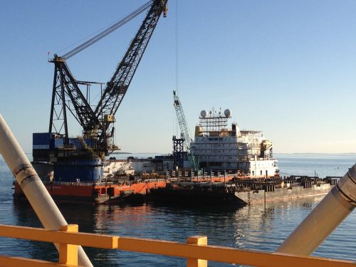 A marine loading arm is seen on a docked barge.