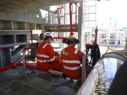 Two Vertech technicians sit on a pipe on the Ichthys Venturer FPSO.