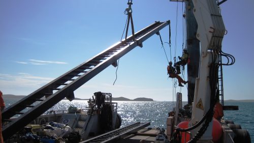 Animage of rope access technicians conducting remediation and repair work on coastal mining infrastructure