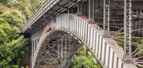 A multi-disciplined team conducting rope access inspection and coating remediation on a bridge in the infrastructure sector.