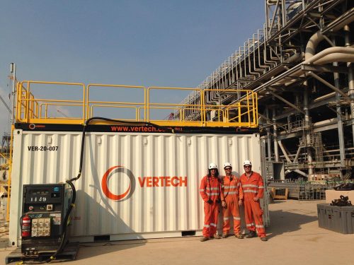 Vertech technicians pose for a photo in front of a branded shipping container.