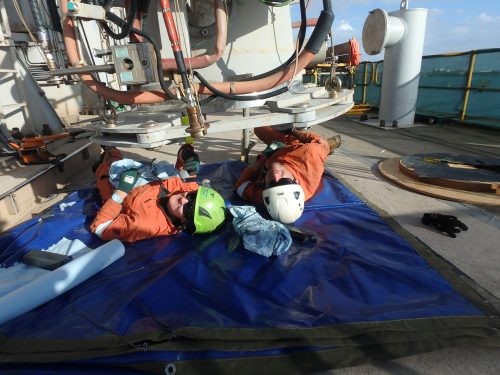 Two vertech technicians lie under a piece of the KGP facility as part of inspections.