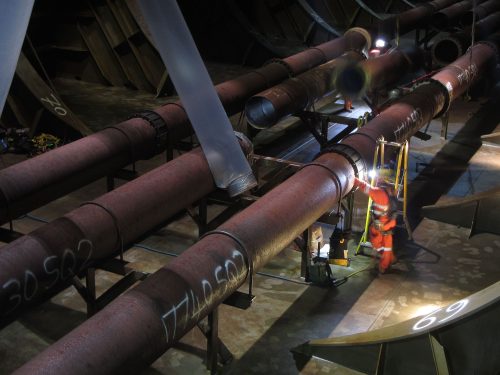 A vertech technician conducting testing on a pipe within the hull.loading=