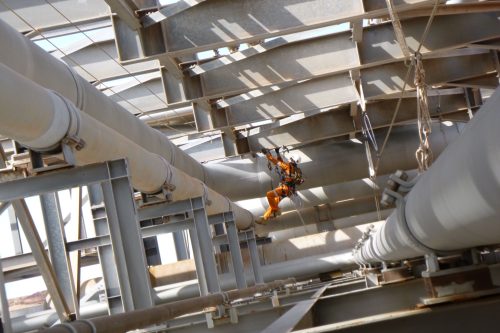 A rope access AICIP inspector is conducting a pressure piping inspection on an LNG asset.