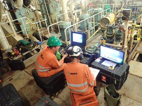 Two vertech technicians view an RDVI crawler camera feed as part of a testing service.