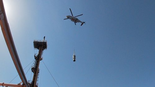 A helicopter carrying material as part of a flare tip changes out on the NRC.