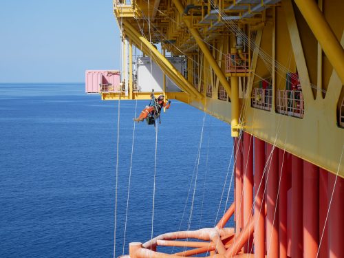 A vertech IRATA rope access technician hangs suspended on ropes from the main platform of the ichthys venturer.