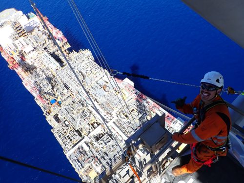A vertech IRATA rope access technician poses for a photo atop the derrick on the ichthys venturer.