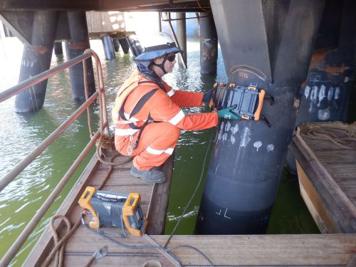 A vertech technician using specialist equipment to map corrosion on a jetty support beam.