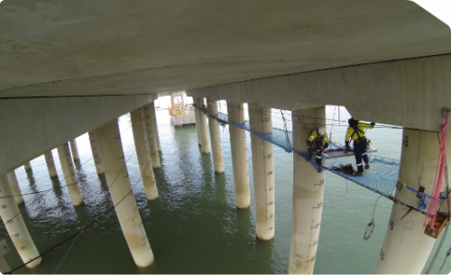 IRATA rope access team installing a tension net on the underside of a jetty to conduct inspection and concrete remediation.