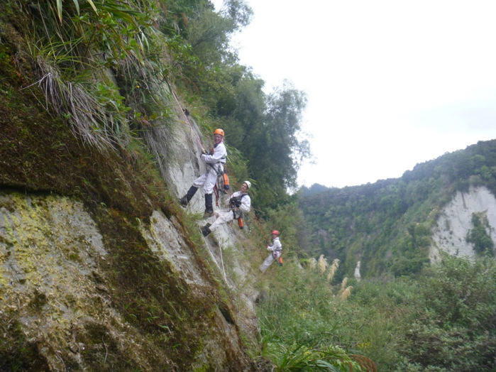 Three smiling Abseil Access rope access technicians on side of cliff.