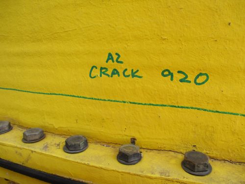 A close up of writing on a piece of yellow metal with "A2 Crack 920" written in green sharpie.