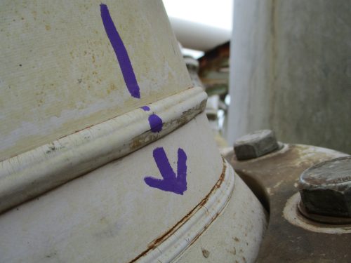 A close up image of white metal refinery equpment with a hand drawn blue arrow pointing down drawn on the front facing side.loading=