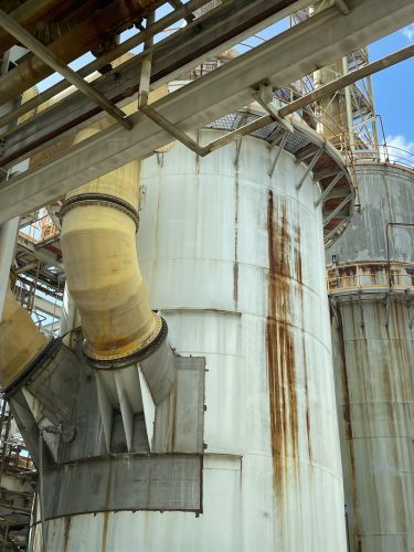 A tank at the Zinc Refinery with a yellow pipe coming out of the left-hand side with a large rust mark running down the centre of it. A tank at the Zinc Refinery with a yellow pipe coming out of the left-hand side with a large rust mark running down the centre of it.