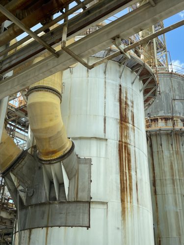 A tank at the Zinc Refinery with a yellow pipe coming out of the left-hand side with a large rust mark running down the centre of it.