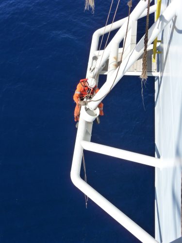 A vertech IRATA Rope Access technician straddles an offshoot of the fpso with water underneath.