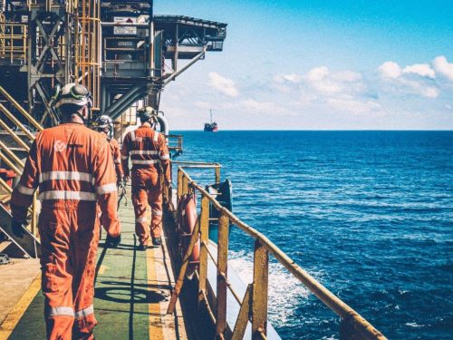 Two vertech technicians walk along the decking of the Ningaloo vision FPSO.