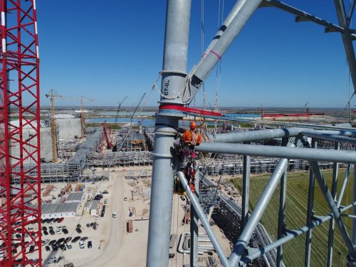 A vertech IRATA rope access technician is attached to a derrick and is conducting a testing procedure.